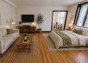 Thumbnail 1 of 23 - A living room with a couch, coffee table, and a bed.