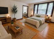 Thumbnail 2 of 23 - A well-lit bedroom with a large bed and a couch.