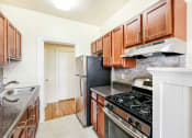 Thumbnail 15 of 29 - kitchen with stainless steel appliances, tile backsplash and wood cabinets at the frontenac apartments in van ness washington dc