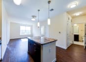 Thumbnail 4 of 21 - kitchen with island, stainless steel appliances, view of living area and hardwood flooring at archer park apartments in southeast Washington dc
