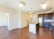 Thumbnail 5 of 21 - vacant living area with hardwood floors, view of kitchen with stainless steel appliances and kitchen island at archer park apartments in southeast Washington dc