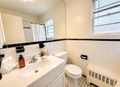 Thumbnail 23 of 23 - A white bathroom with a toilet, sink, and a window.
