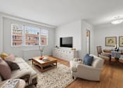 Thumbnail 6 of 23 - A living room with a couch, a coffee table, and a television.