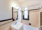 Thumbnail 11 of 20 - bathroom with tub, vanity, large mirror, tile details and window at baystate apartments in washington dc