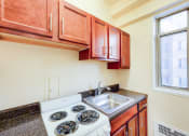 Thumbnail 4 of 20 - kitchen with window, wood cabinetry and electric range at baystate apartments in washington dc