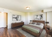 Thumbnail 8 of 18 - a bedroom with white walls and wood floors and a bed