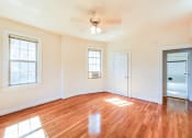 Thumbnail 20 of 29 - vacant bedroom with hardwood floors, ceiling fan, large windows and view of bathroom at the frontenac apartments in van ness washington dc