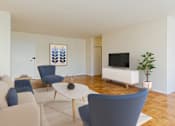 Thumbnail 13 of 47 - A living room with a white sofa, blue chairs, and a television.