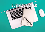 Thumbnail 9 of 11 - A business center setup with a laptop, mouse, and glasses on a notepad.