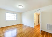 Thumbnail 18 of 23 - vacant living area with large windows, hard wood flooring and view of hallway in cambridge square apartments in bethesda md