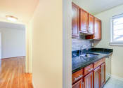 Thumbnail 3 of 23 - kitchen with wood cabinetry, tile backsplash, and window at cambridge square apartments in bethesda md