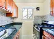 Thumbnail 2 of 23 - kitchen with wood cabinetry, gas range, tile backsplash, and window at cambridge square apartments in bethesda md