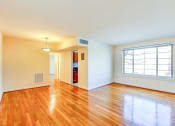 Thumbnail 16 of 23 - vacant living area with large windows, hard wood flooring and  view of kitchen in cambridge square apartments in bethesda md