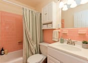 Thumbnail 10 of 24 - A bathroom with a white toilet, a white sink, and a shower with a green curtain.