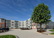 Thumbnail 17 of 20 - A large grey building with a black car parked in front.