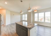Thumbnail 13 of 18 - view of kitchen with island and vacant living area with large windows and hardwood floors at city view apartments in washington dc
