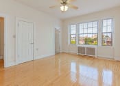 Thumbnail 14 of 25 - an empty living room with a ceiling fan, hardwood floors and three windows at the calverton apartments in washington dc