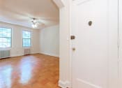 Thumbnail 10 of 17 - entrance to apartment unit with view of living area with large windows, ceiling fan and hardwood floors at 1400 van buren apartments in washington dc