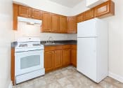 Thumbnail 3 of 17 - kitchen with oak cabinetry, tile flooring and white appliances at 1400 van buren apartments in washington dc