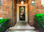 Thumbnail 13 of 17 - entrance of 1400 van buren apartments with lush landscaping, brick building and sidewalk