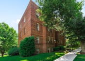Thumbnail 14 of 17 - exterior of 1400 van buren apartments with lush landscaping, brick building and sidewalk