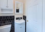 Thumbnail 16 of 21 - bathroom with toilet, sink, cabinetry and mirror at 6100 14th Street apartments in washington dc