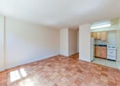 Thumbnail 9 of 16 - vacant living area with hardwood floors and view of kitchen at alpha house apartments in washington dc