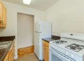 Thumbnail 3 of 24 - kitchen with tile flooring, refrigerator, gas stove and  oak cabinetry at chillum place apartments in lamond riggs washington dc