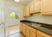 Thumbnail 6 of 24 - kitchen with tile flooring, refrigerator, gas stove, oak cabinetry, and view of dining area at chillum place apartments in lamond riggs washington dc