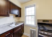 Thumbnail 1 of 21 - kitchen with espresso cabinetry, radiator, gas range and window at the colonnade apartments in washington dc