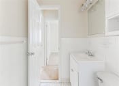 Thumbnail 5 of 13 - bathroom with white toilet, vanity, large mirror and cabinetry at halley house apartments in washington dc