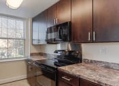Thumbnail 4 of 21 - kitchen with espresso cabinetry, window and energy efficient appliances at juniper courts apartments in takoma washington dc