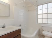 Thumbnail 11 of 21 - bathroom with tub, toilet, vanity, window and mirror at juniper courts apartments in takoma washington dc