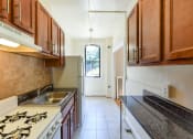 Thumbnail 1 of 28 - kitchen with wood cabinetry and tile backsplash at the klingle apartments in washignton dc