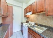 Thumbnail 2 of 28 - kitchen with wood cabinetry and tile backsplash at the klingle apartments in washignton dc