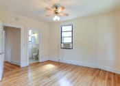 Thumbnail 23 of 28 - vacant bedroom with hardwood floors, large window, ceiling fan and view of bathroom at the klingle apartments in washignton dc