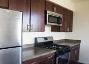Thumbnail 5 of 6 - kitchen with espresso cabinetry, stainless steel appliances, and breakfast bar at sheridan station apartments in washington dc