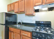 Thumbnail 4 of 35 - kitchen with wood cabinetry, gas stove, and granite countertops at dupont apartments in washington dc