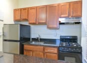 Thumbnail 3 of 35 - kitchen with wood cabinetry, gas stove, and granite countertops at dupont apartments in washington dc