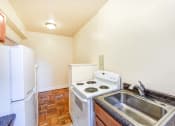 Thumbnail 4 of 20 - kitchen with wood cabinetry, electric range and refrigerator at eddystone apartments in washington dc