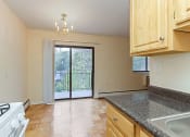Thumbnail 5 of 19 - kitchen with wood cabinetry, energy efficient appliances and view of dining area and balcony at fort totten apartments in washington dc