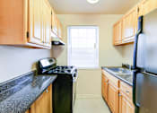 Thumbnail 8 of 24 - A kitchen with wooden cabinets and black appliances.