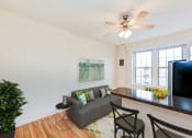 Thumbnail 7 of 25 - a living room with a couch and a table and a ceiling fan
