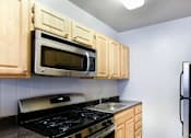 Thumbnail 8 of 19 - A kitchen with wooden cabinets and a black stove top.