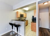 Thumbnail 3 of 19 - A kitchen with a bar stool and a microwave above the bar.