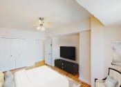 Thumbnail 4 of 19 - bedroom with bed, tv, dresser, ceiling fan, and sitting area at hilltop house apartments in columbia heights washington dc