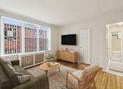 Thumbnail 2 of 17 - A living room with a couch, chair, and television.