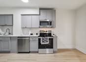 Thumbnail 38 of 64 - A kitchen with a stove top oven and microwave above it.