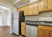 Thumbnail 31 of 43 - A kitchen with wooden cabinets and a black fridge.