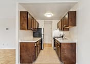 Thumbnail 15 of 36 - A kitchen with brown cabinets and a black refrigerator.